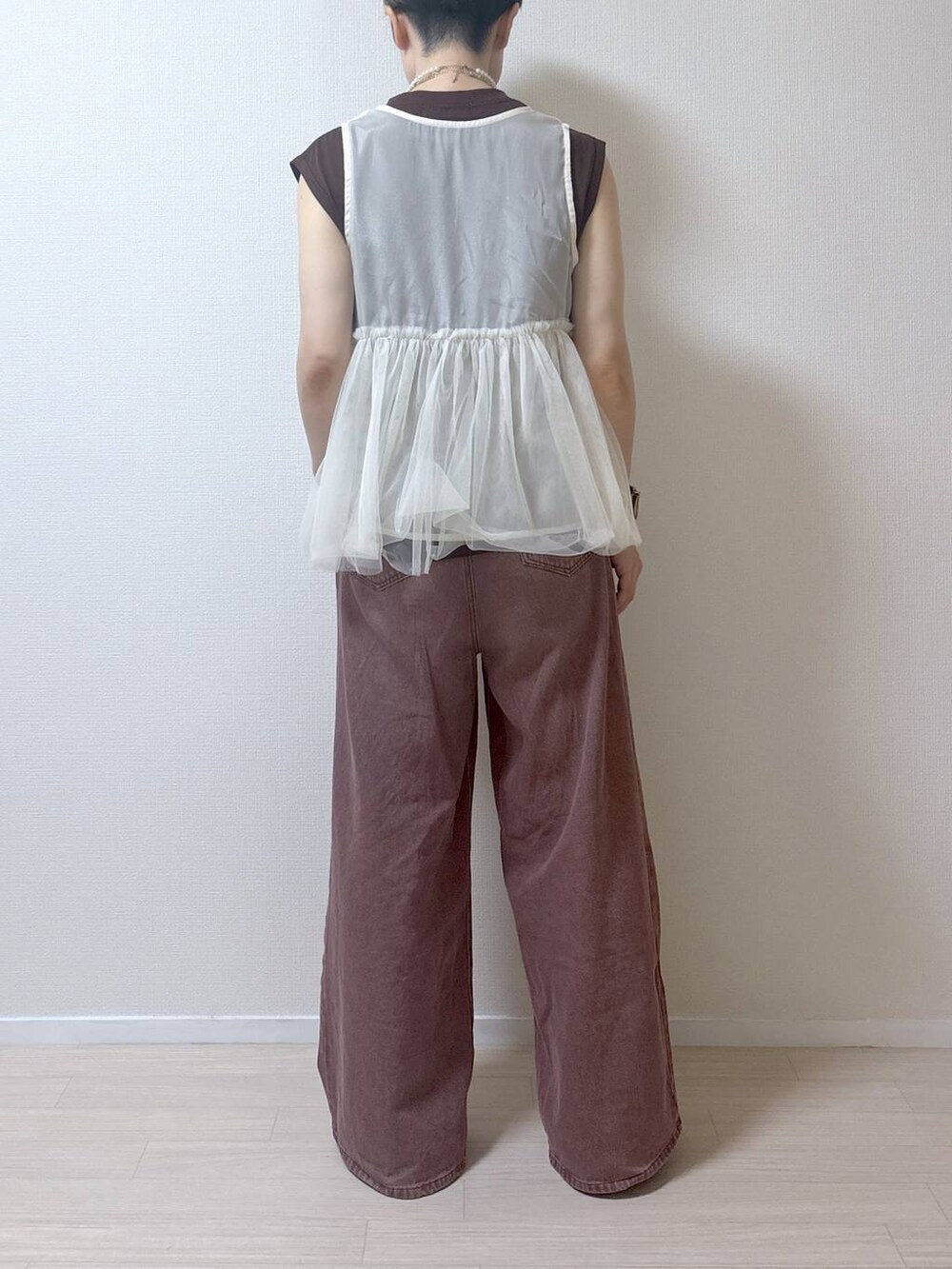 ベージュ系のベスト、ブラウン系のデニムパンツを着用したレディースの夏コーディネートの5枚目の写真