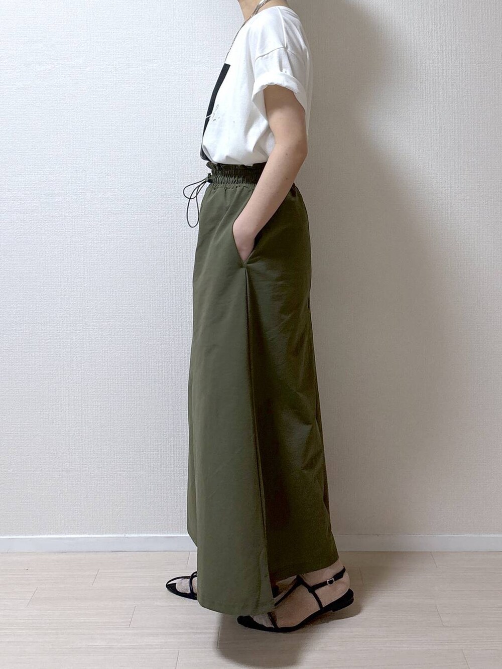 ブラック系のサンダル、ホワイト系のTシャツ/カットソー、グリーン系のスカートを着用したレディースの春コーディネートの6枚目の写真