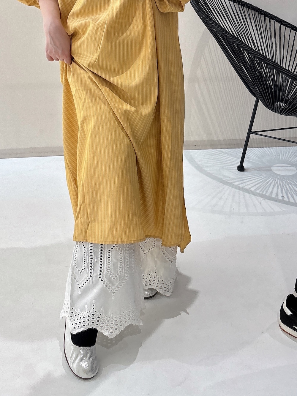 シルバー系のバレエシューズ、イエロー系のワンピース、ホワイト系のパンツを着用したレディースの冬コーディネートの5枚目の写真