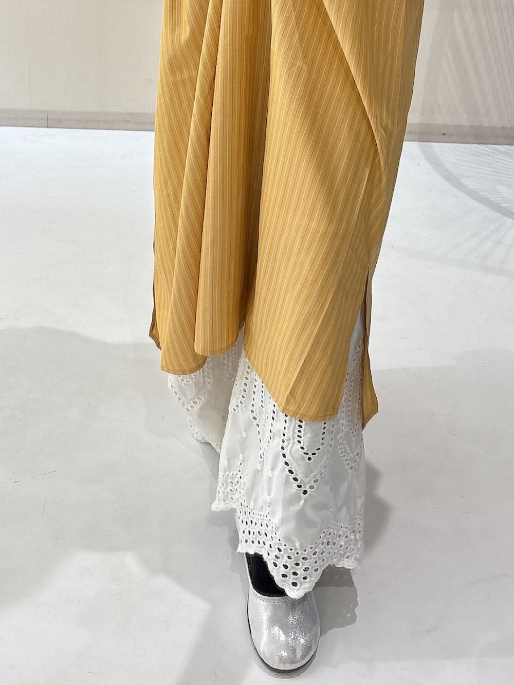 シルバー系のバレエシューズ、イエロー系のワンピース、ホワイト系のパンツを着用したレディースの冬コーディネートの4枚目の写真