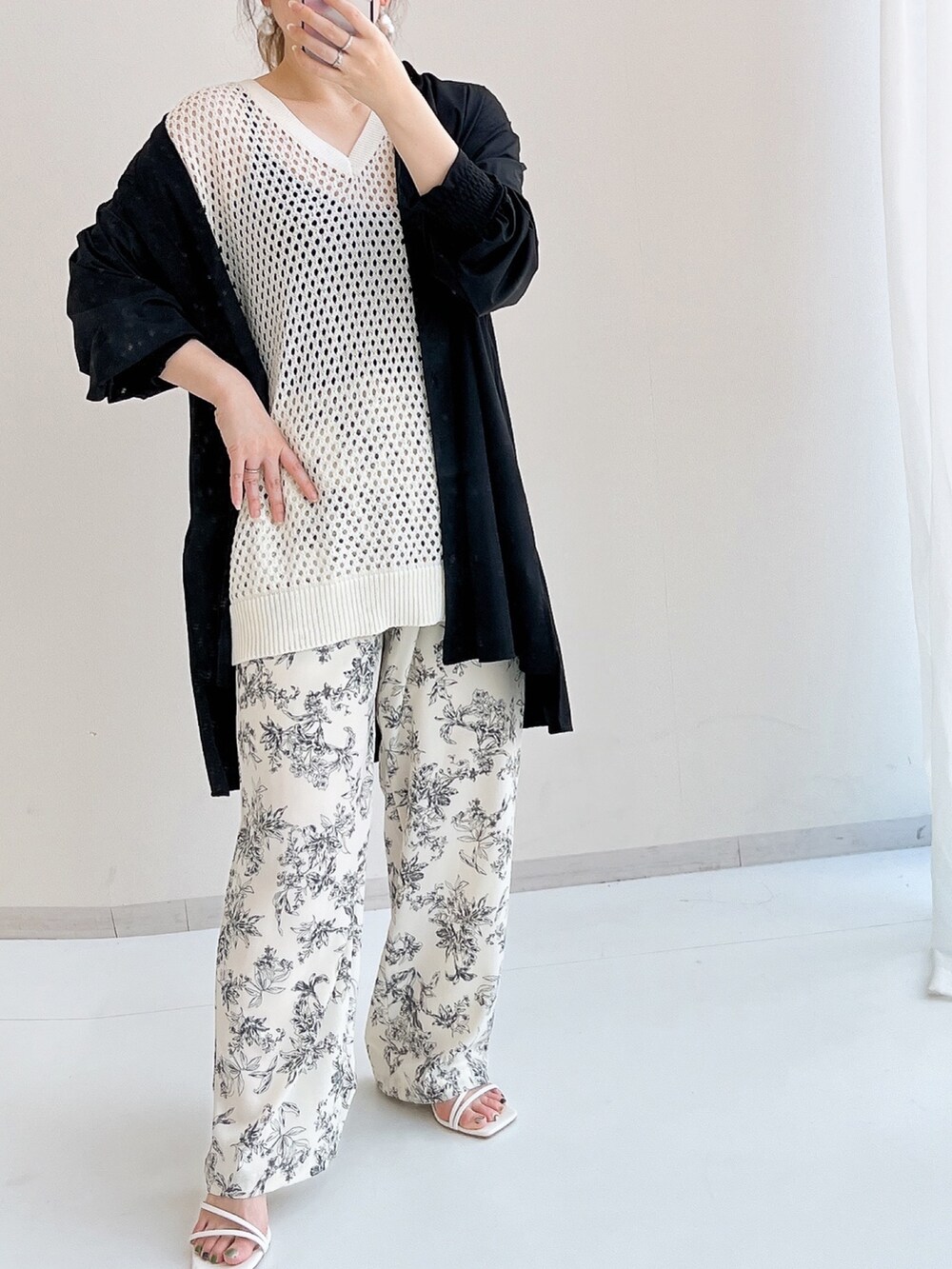 ホワイト系のパンツ、ホワイト系のニット/セーター、ブラック系のラッシュガードを着用したレディースの夏コーディネートの2枚目の写真