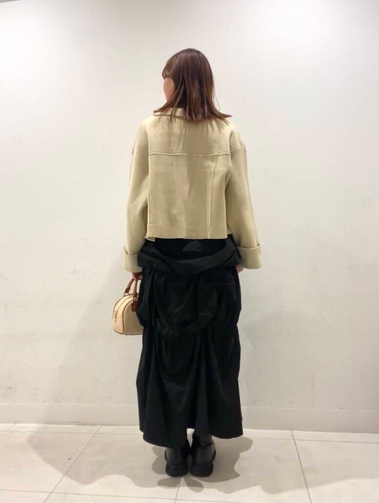 ブラック系のスカート、イエロー系のボストンバッグ、ベージュ系のニット/セーターを着用したレディースの冬コーディネートの2枚目の写真