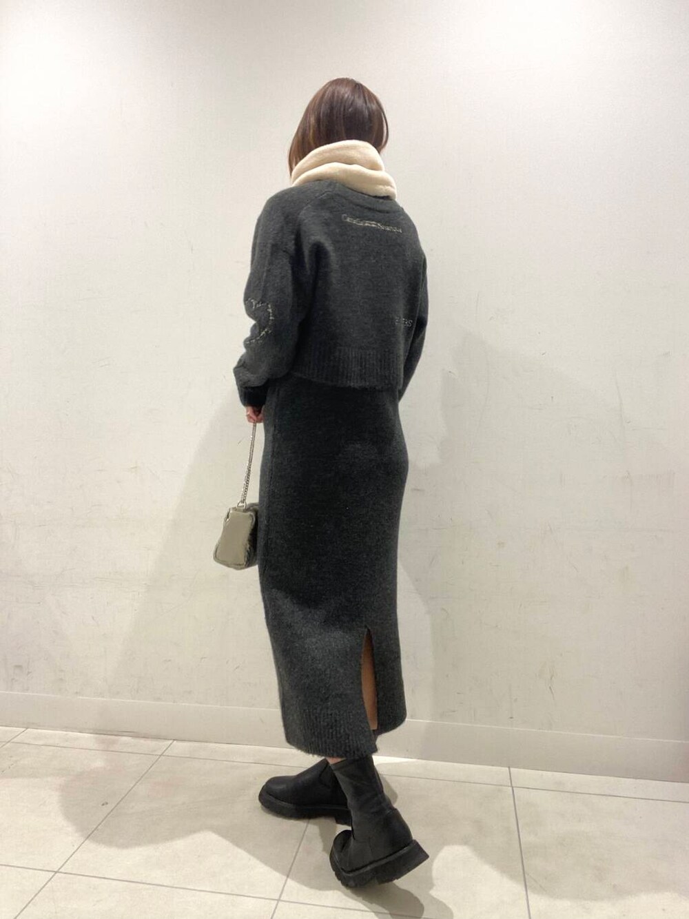 シルバー系のショルダーバッグ、グレー系のワンピース、ホワイト系のマフラーを着用したレディースの冬コーディネートの3枚目の写真