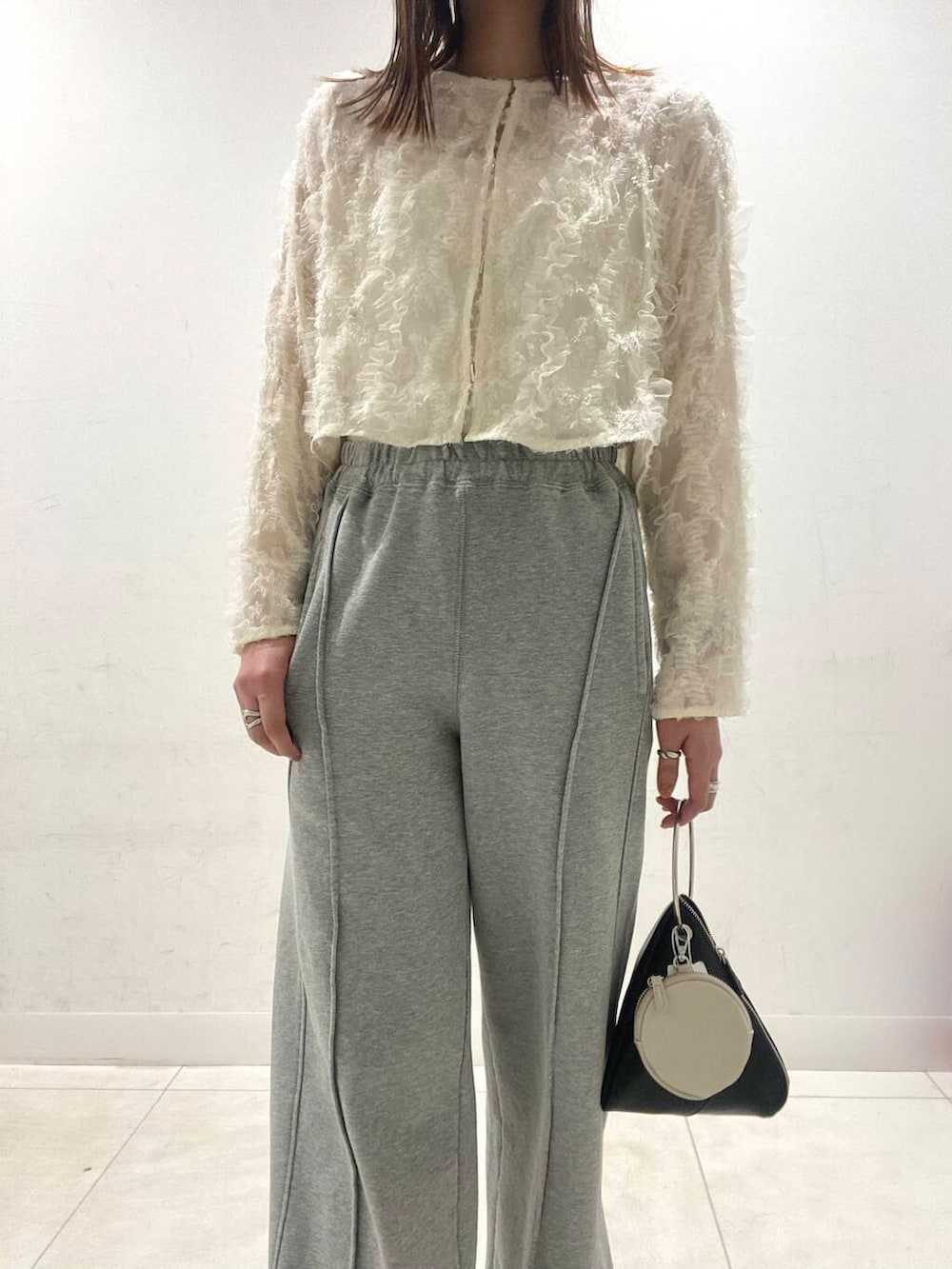 ブラック系のパンプス、ブラック系のハンドバッグ、ホワイト系のキャミソールを着用したレディースの春コーディネートの3枚目の写真