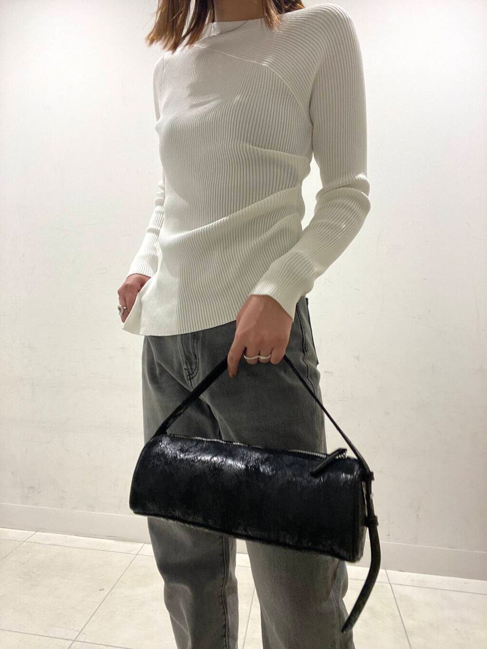 グレー系のデニムパンツ、ブラック系のハンドバッグ、ホワイト系のニット/セーターを着用したレディースの冬コーディネートの3枚目の写真