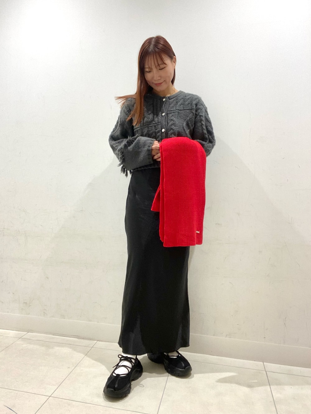 グレー系のカーディガン/ボレロ、ブラック系のスカート、ブラック系のスニーカーを着用したレディースの秋コーディネートの2枚目の写真