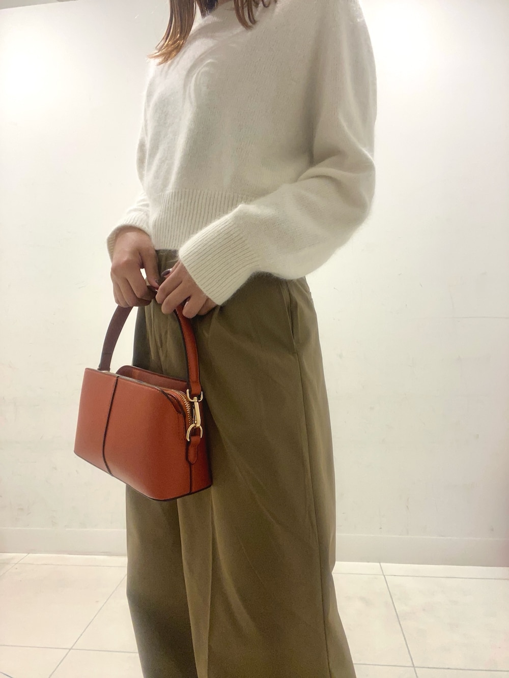 ホワイト系のニット/セーター、ベージュ系のその他パンツ、オレンジ系のショルダーバッグを着用したレディースの秋コーディネートの4枚目の写真
