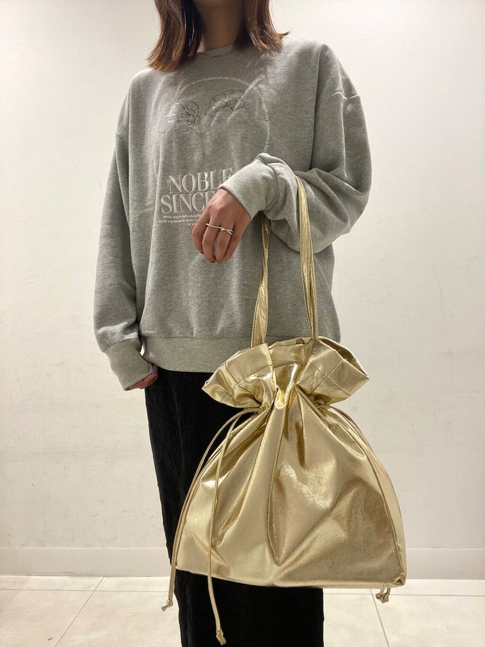 ゴールド系のトートバッグ、ブラック系のスカート、その他のスウェットを着用したレディースの冬コーディネートの4枚目の写真