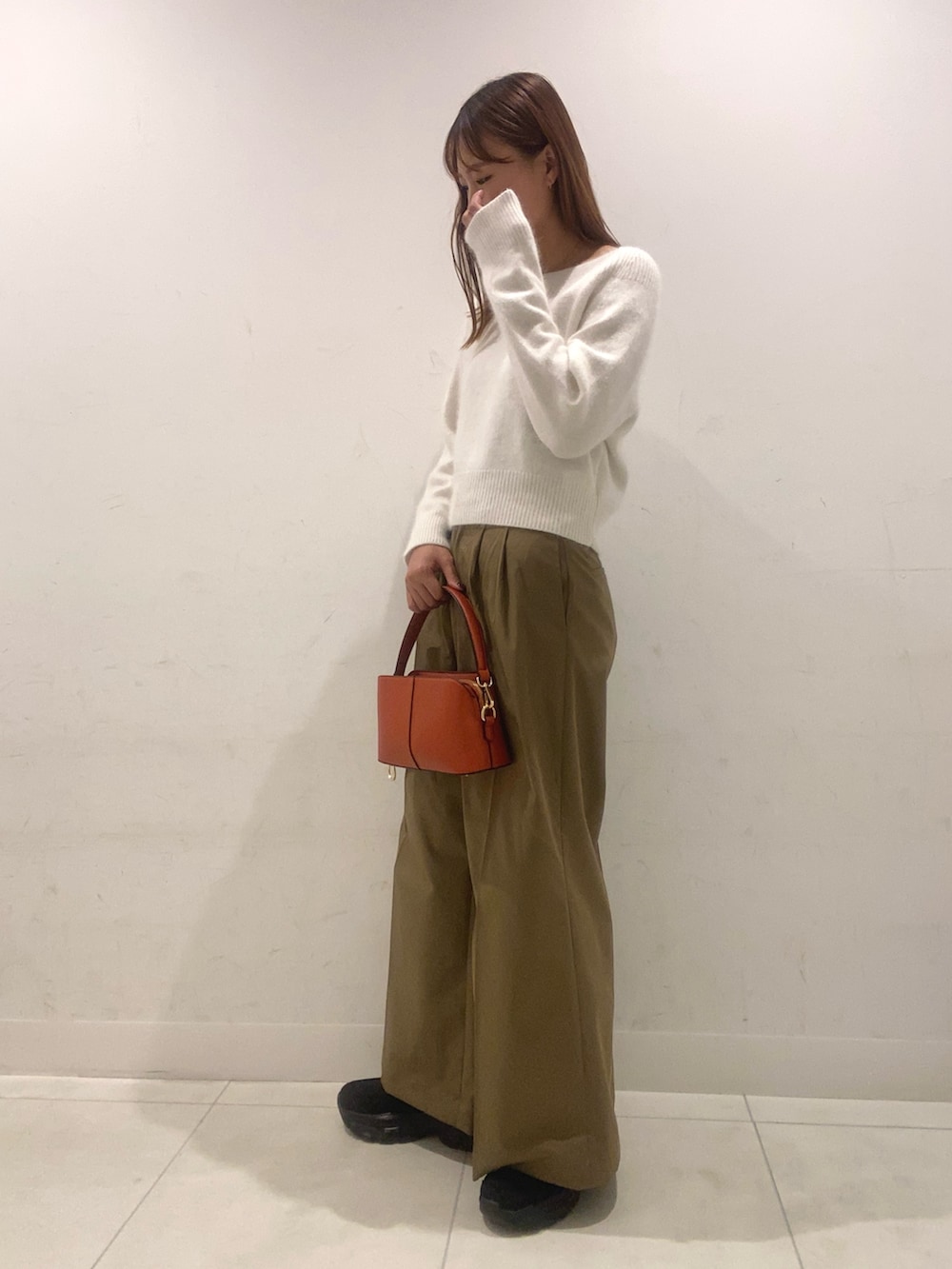 ホワイト系のニット/セーター、ベージュ系のその他パンツ、オレンジ系のショルダーバッグを着用したレディースの秋コーディネートの2枚目の写真