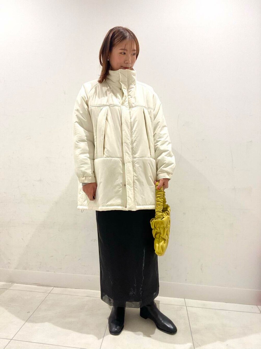 イエロー系のハンドバッグ、ブラック系のブーツ、その他のスウェットを着用したレディースの冬コーディネートの2枚目の写真