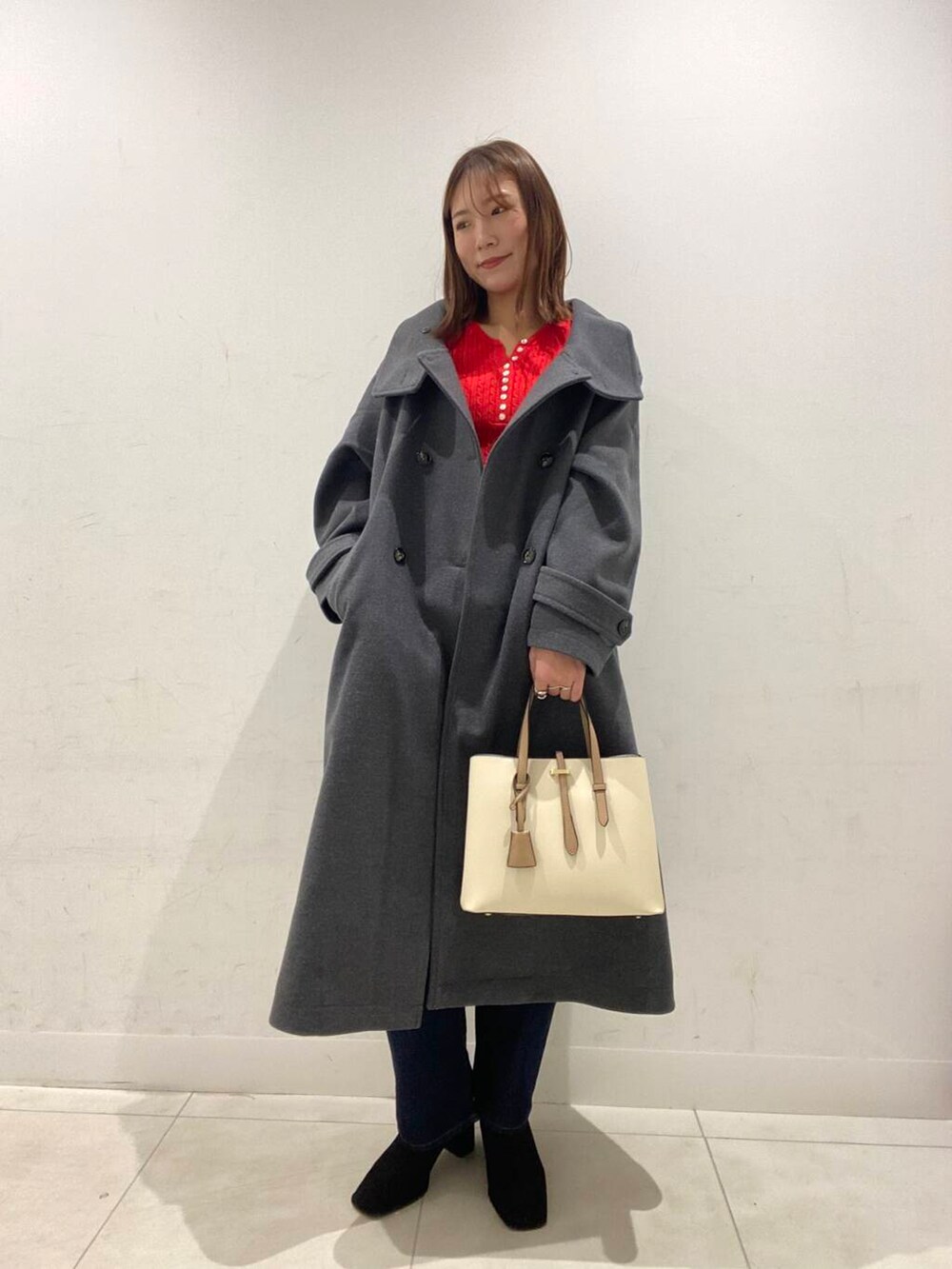ホワイト系のトートバッグ、ブラック系のブーツ、グレー系のその他アウターを着用したレディースの冬コーディネートの2枚目の写真