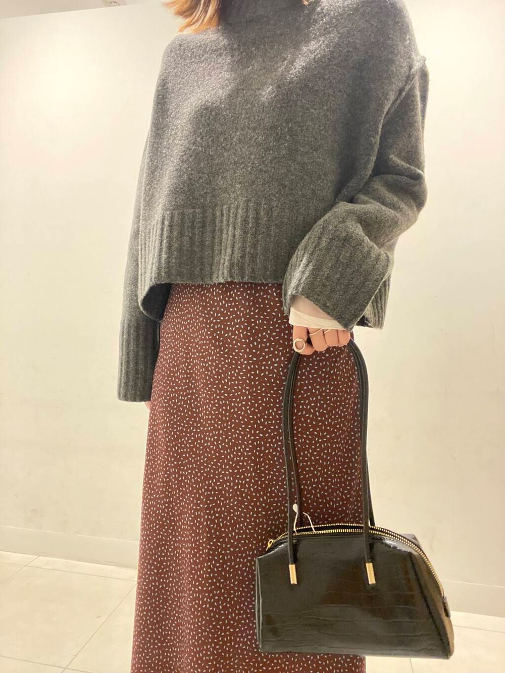 ブラック系のブーツ、ブラック系のハンドバッグ、ブラウン系のスカートを着用したレディースの冬コーディネートの2枚目の写真