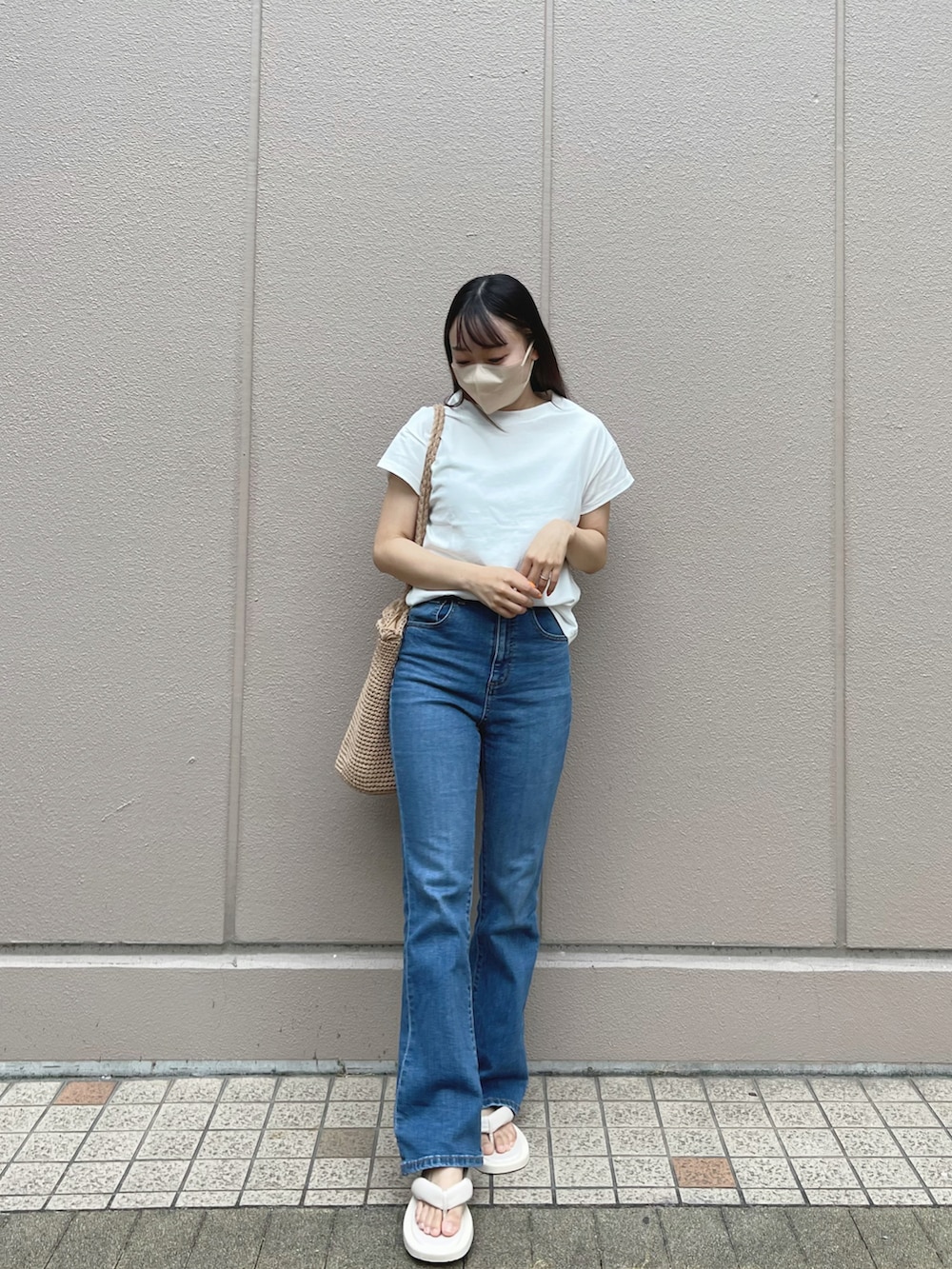ホワイト系のTシャツ/カットソー、ブルー系のデニムパンツ、ベージュ系のトートバッグを着用したレディースの夏コーディネートの2枚目の写真