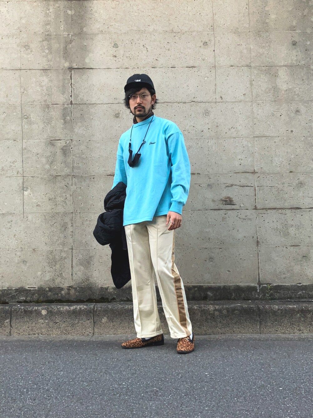 ブラック系のモッズコート、ブルー系のTシャツ/カットソー、ベージュ系のデニムパンツを着用したメンズの春コーディネートの4枚目の写真