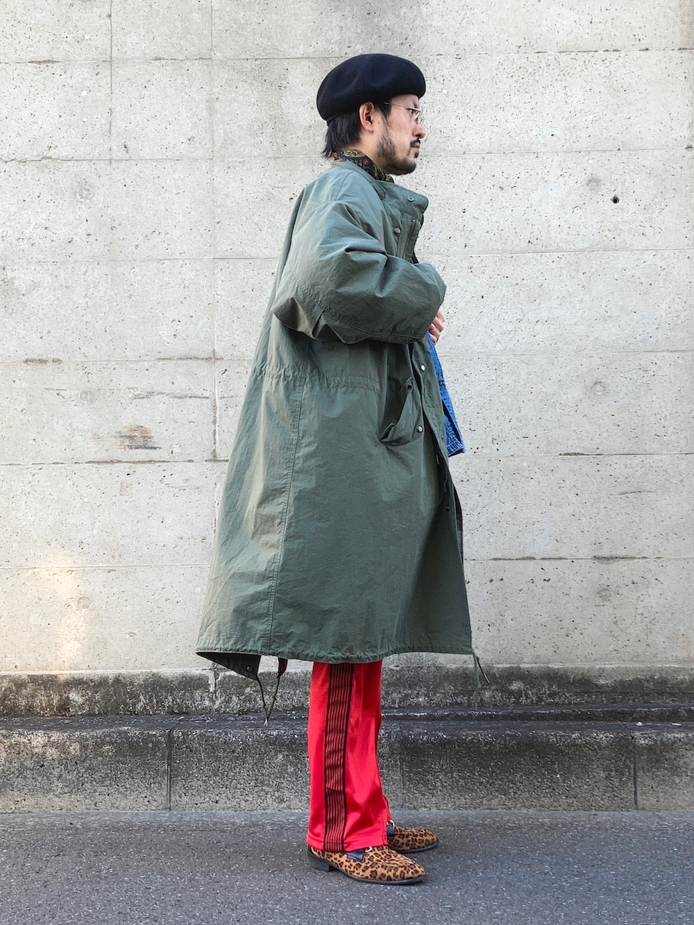 グリーン系のモッズコート、ブルー系のカバーオール、レッド系のデニムパンツを着用したメンズの冬コーディネートの2枚目の写真