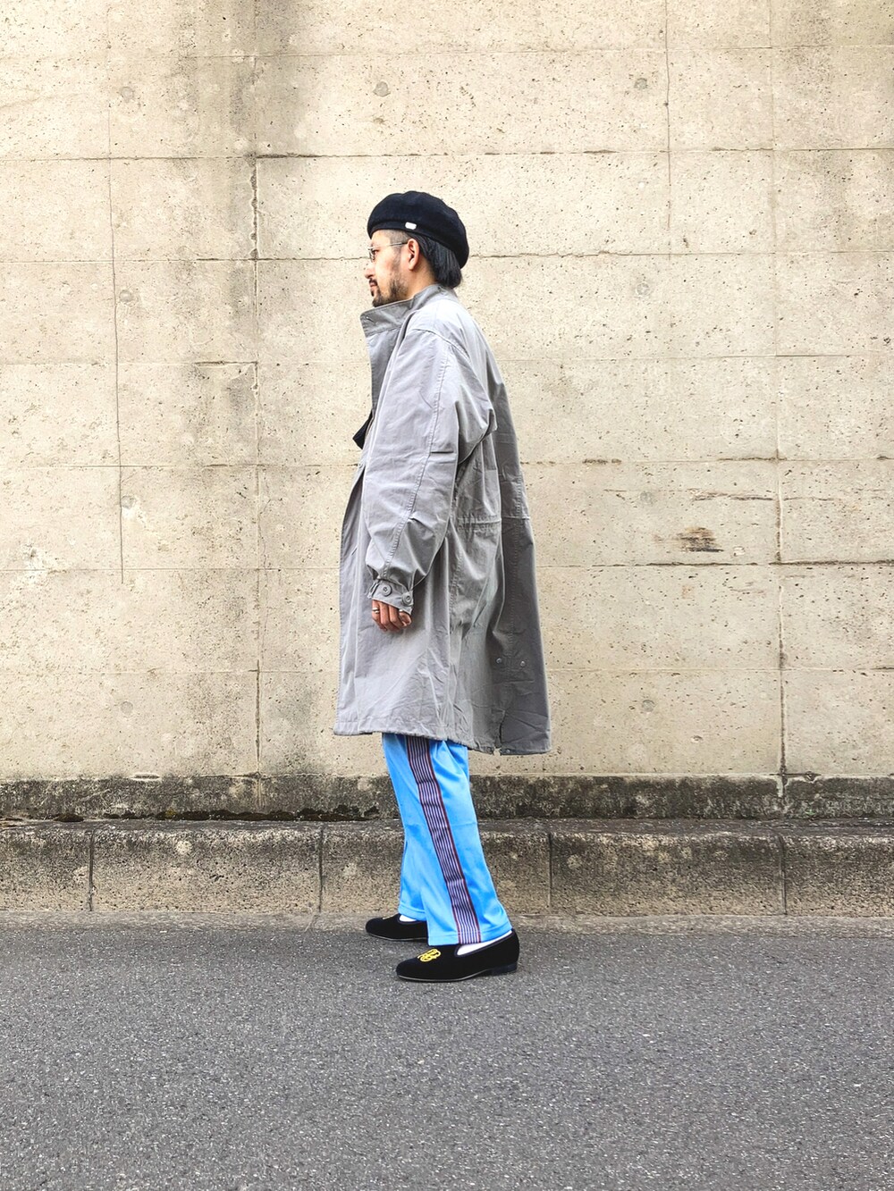 グレー系のモッズコート、イエロー系のスウェット、ブルー系のデニムパンツを着用したメンズの春コーディネートの2枚目の写真