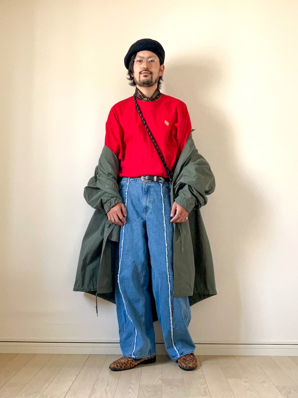 グリーン系のモッズコート、レッド系のTシャツ/カットソー、ブルー系のデニムパンツを着用したメンズの春コーディネートの3枚目の写真