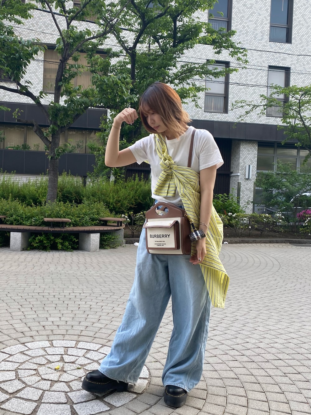 ブラック系のブーツ、イエロー系のシャツ/ブラウス、ブルー系のデニムパンツを着用したレディースの春コーディネートの2枚目の写真