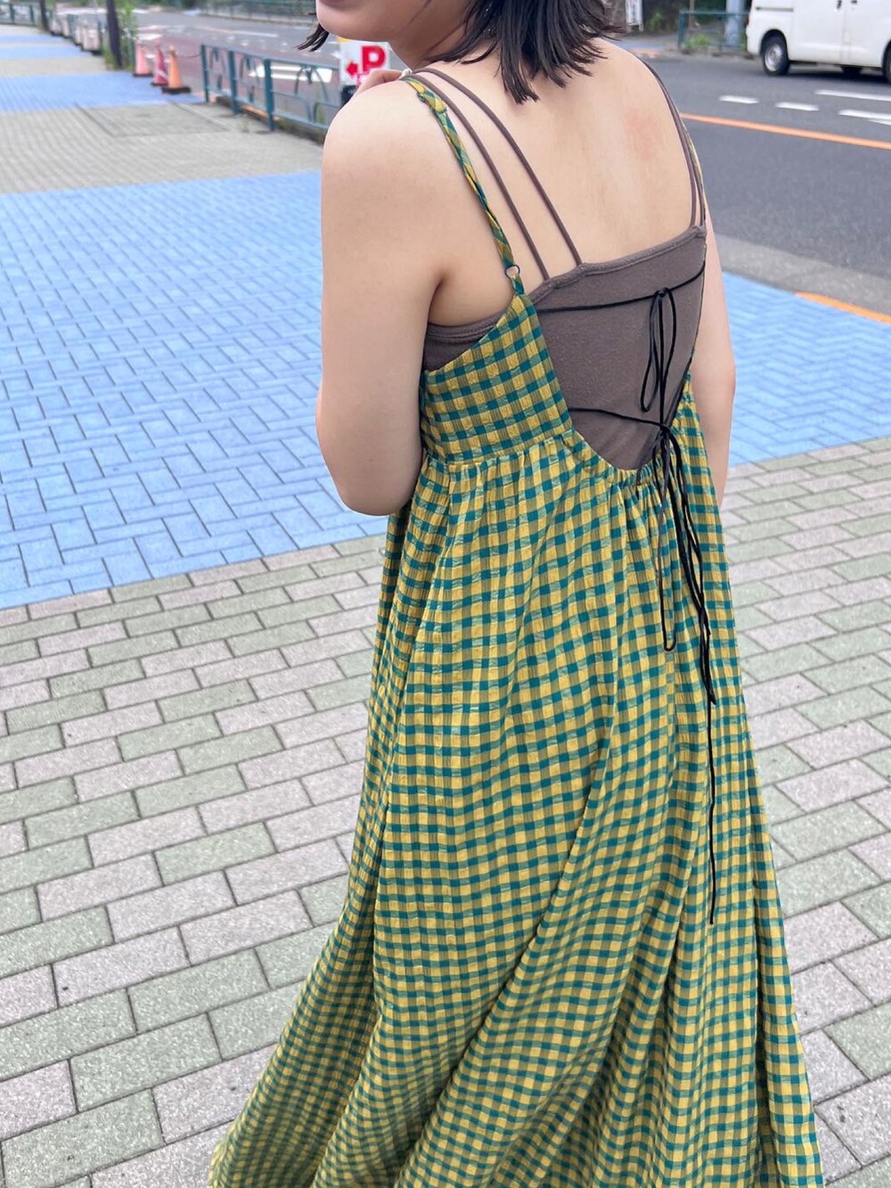 イエロー系のワンピース、ブラック系のパンプス、ブラウン系のキャミソールを着用したレディースの夏コーディネートの2枚目の写真