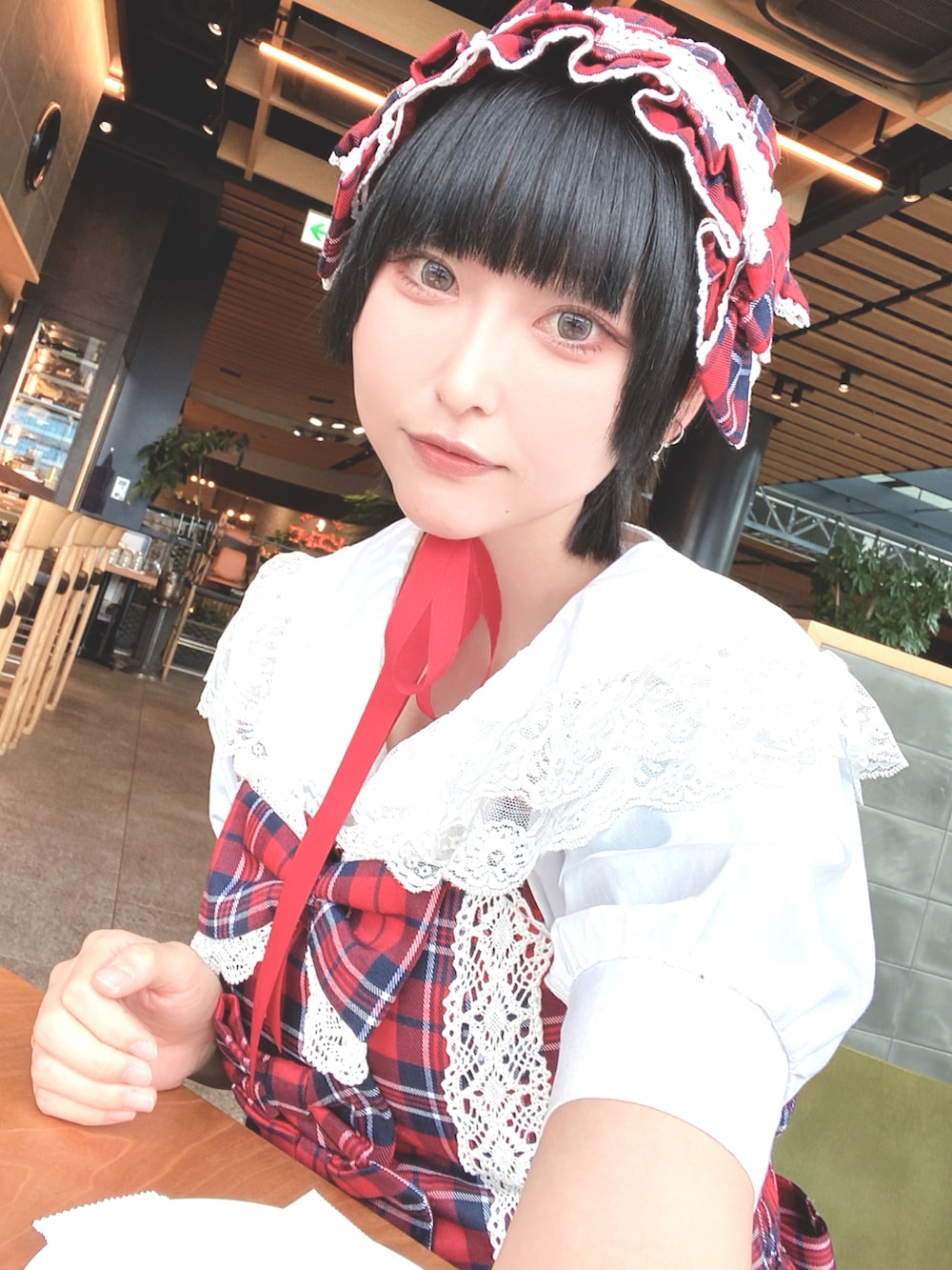 ブラック系のローファー、レッド系のジャンパースカート、ブルー系のボストンバッグを着用したレディースの春コーディネートの2枚目の写真