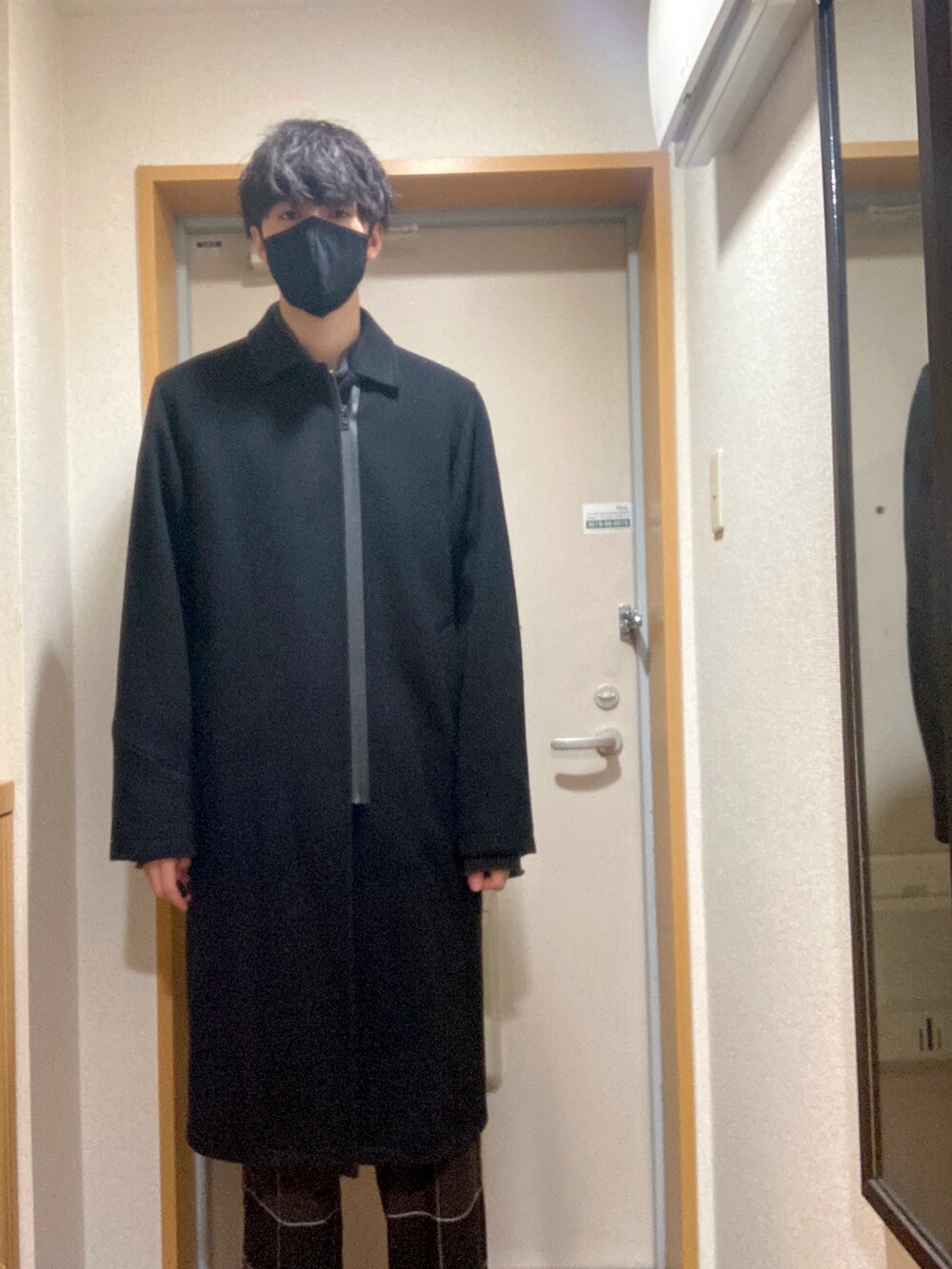 ブラック系のステンカラーコート、グレー系のニット/セーター、ブラック系のその他パンツを着用したメンズの冬コーディネートの2枚目の写真