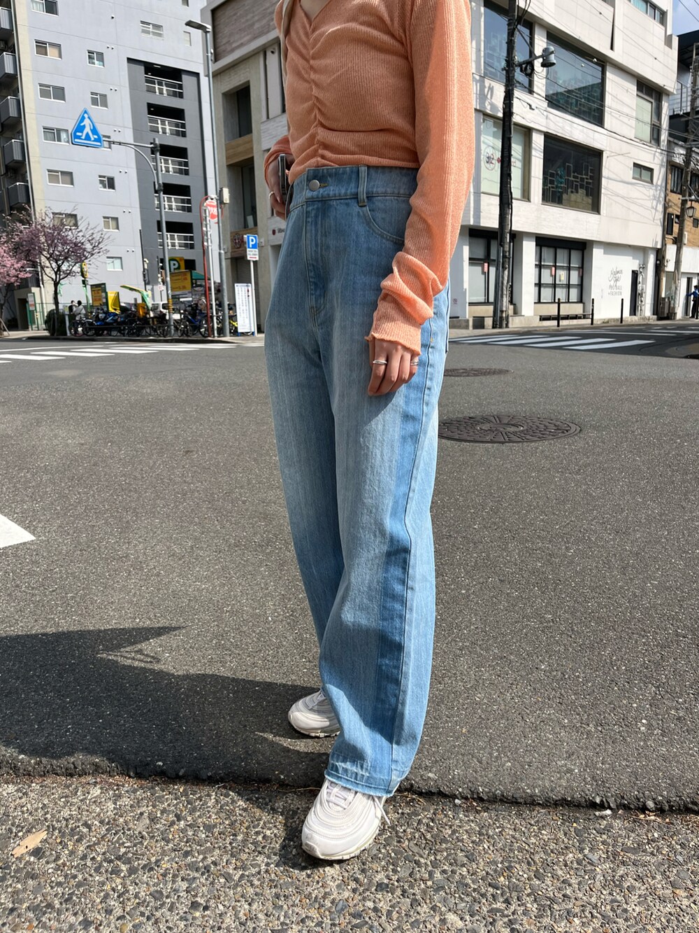 オレンジ系のTシャツ/カットソー、ブルー系のデニムパンツ、ベージュ系のトートバッグを着用したレディースの春コーディネートの2枚目の写真