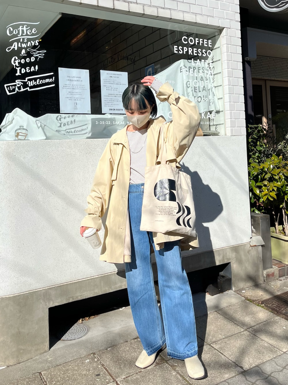 ホワイト系のTシャツ/カットソー、ホワイト系のトレンチコート、ブルー系のデニムパンツを着用したレディースの冬コーディネートの2枚目の写真