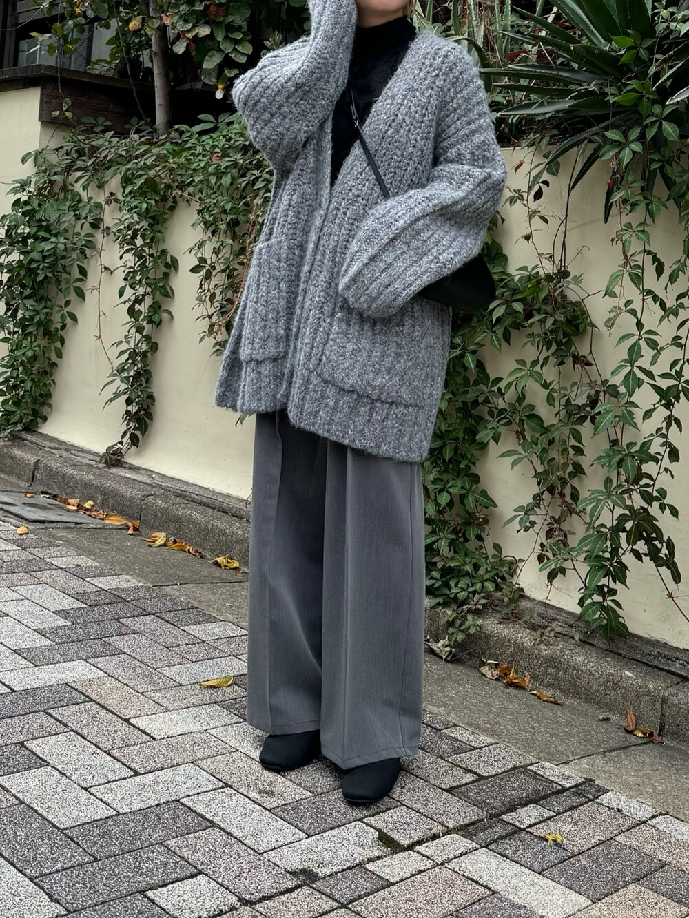 グレー系のカーディガン/ボレロ、グレー系のスラックス、ブラック系のニット/セーターを着用したレディースの秋コーディネートの2枚目の写真