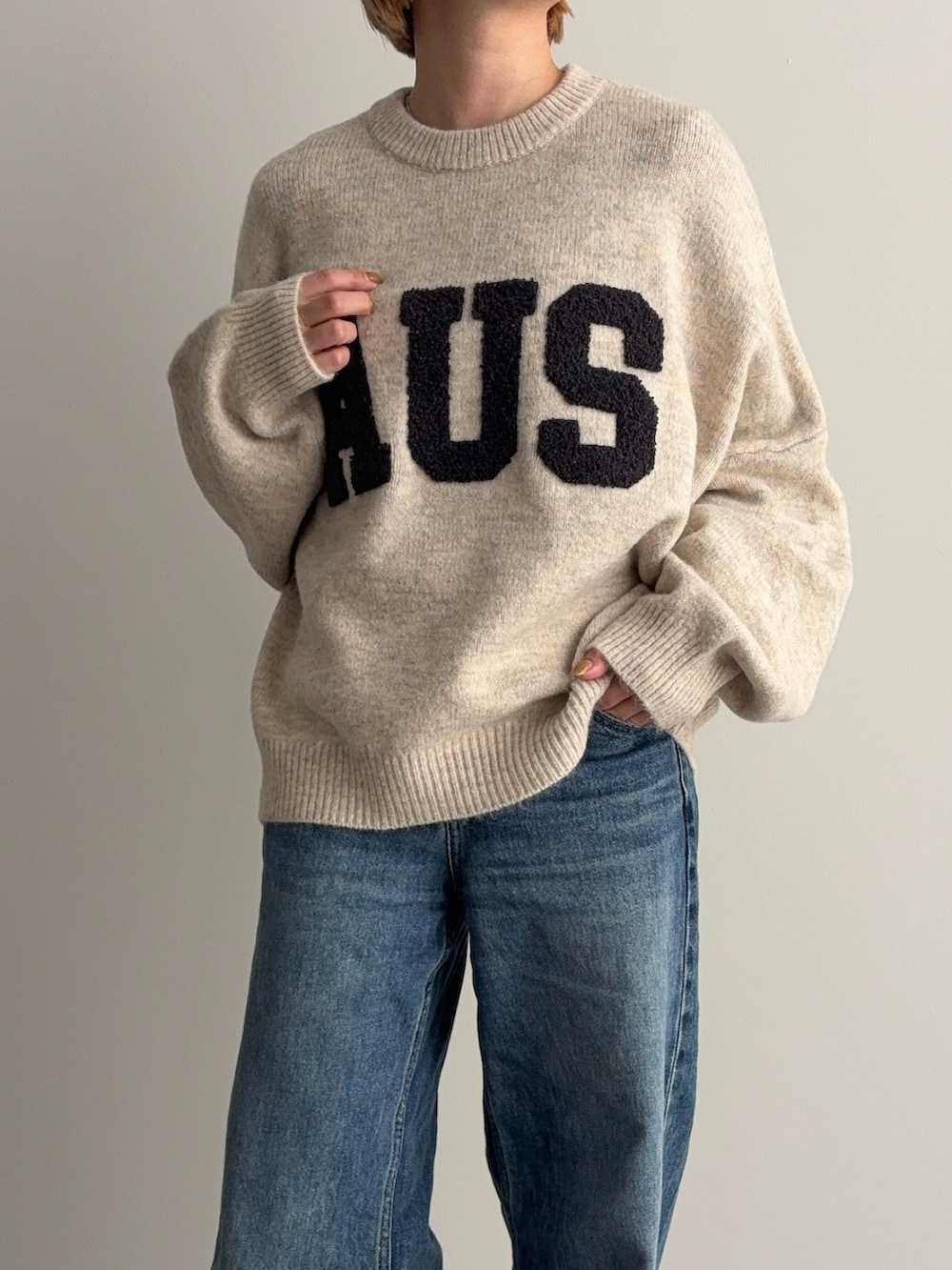 ブルー系のデニムパンツ、ベージュ系のシューズ、ベージュ系のニット/セーターを着用したレディースの秋コーディネートの2枚目の写真