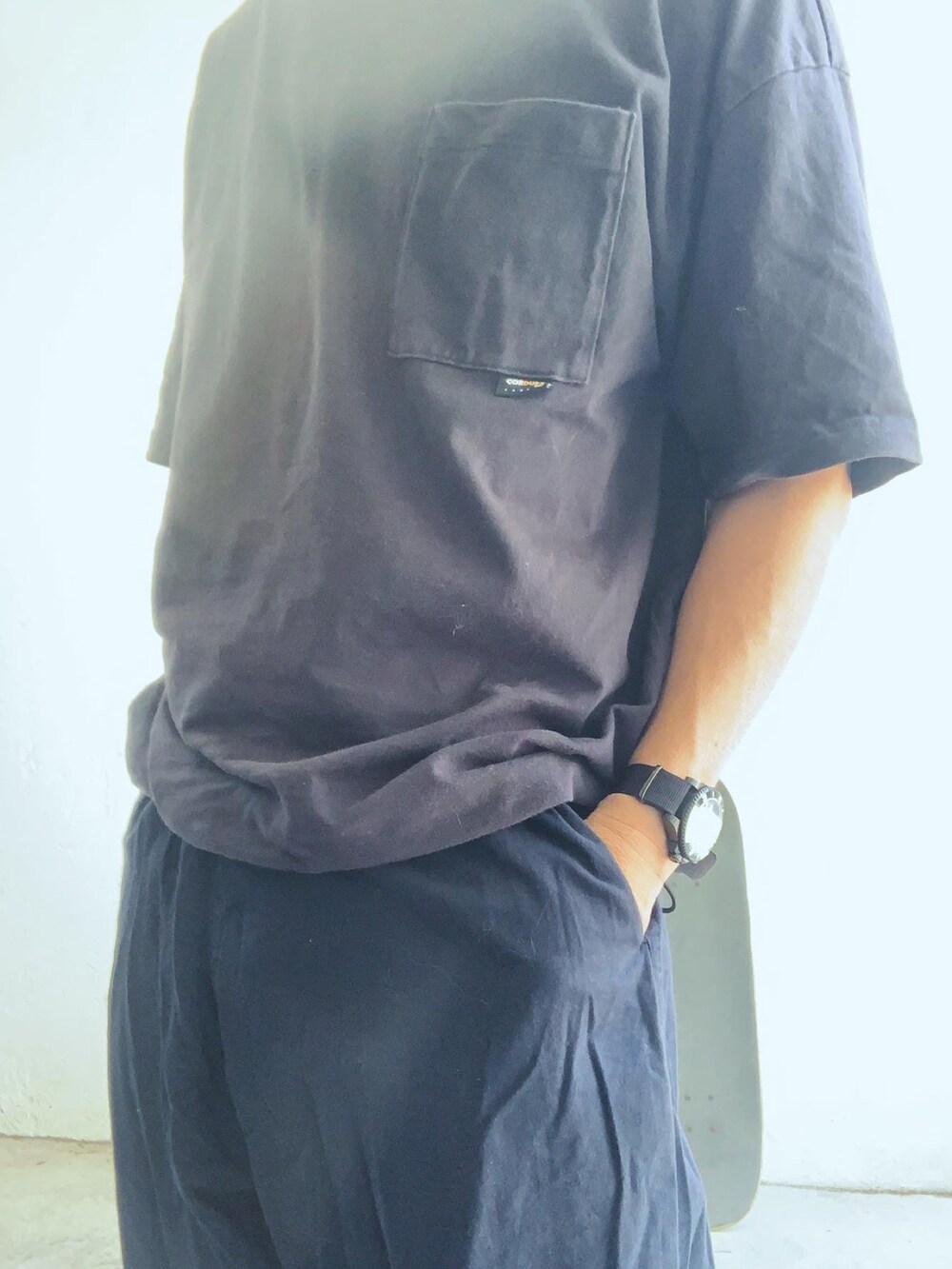 ブラック系のTシャツ/カットソー、ブルー系のパンツ、ブラック系のスニーカーを着用したメンズの夏コーディネートの3枚目の写真