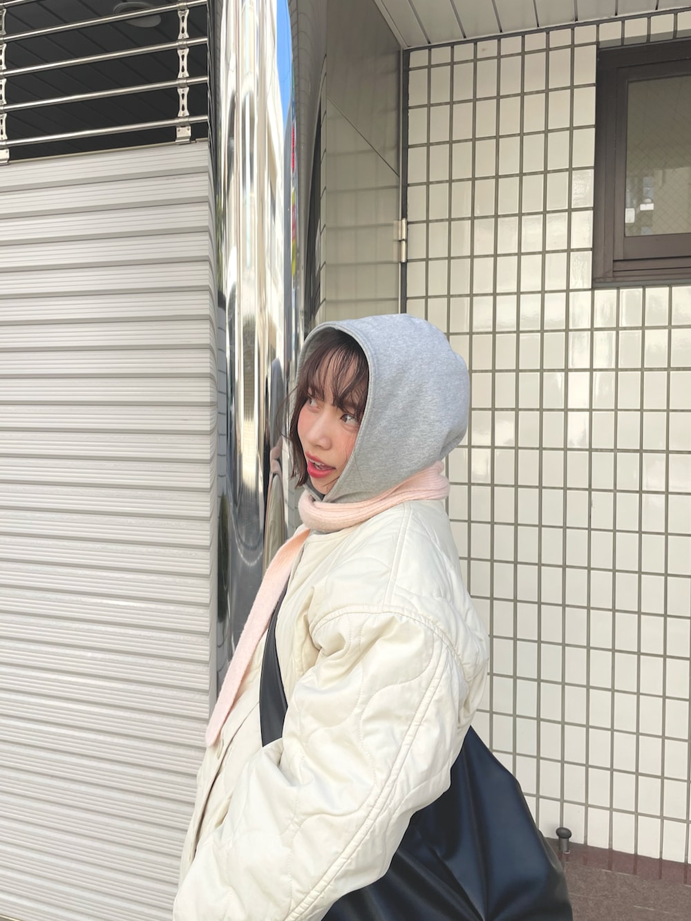 ベージュ系のスニーカー、ホワイト系のブルゾン、ブラック系のショルダーバッグを着用したレディースの春コーディネートの2枚目の写真