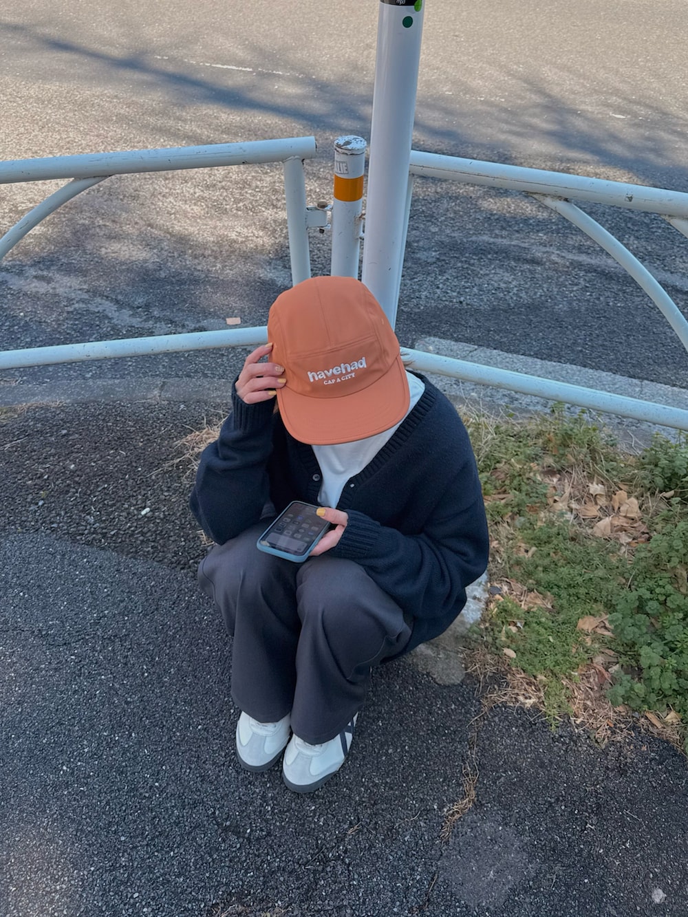 ホワイト系のスニーカー、オレンジ系のキャップを着用したレディースの春コーディネートの3枚目の写真