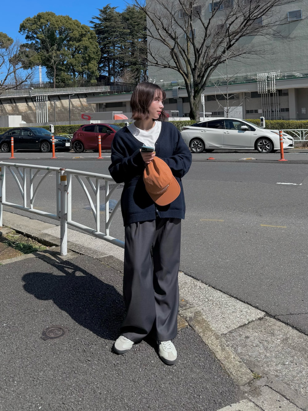 ホワイト系のスニーカー、オレンジ系のキャップを着用したレディースの春コーディネートの2枚目の写真