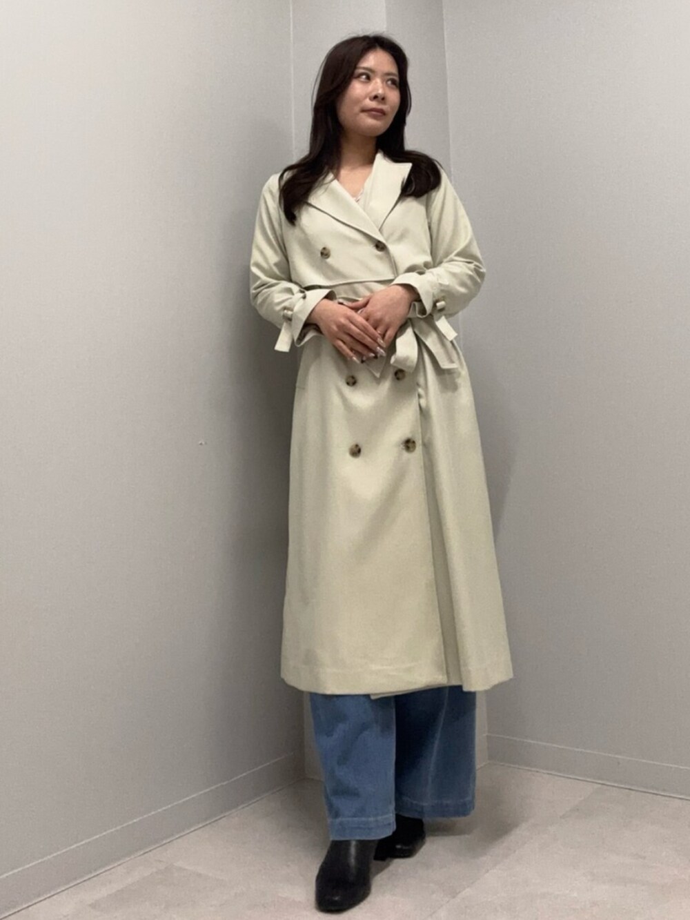 ブルー系のデニムパンツ、ベージュ系のトレンチコートを着用したレディースの春コーディネートの2枚目の写真
