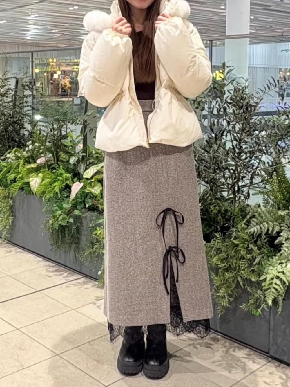 ブラウン系のスカート、ブラウン系のニット/セーター、ホワイト系のダウンジャケット/コートを着用したレディースの冬コーディネートの2枚目の写真