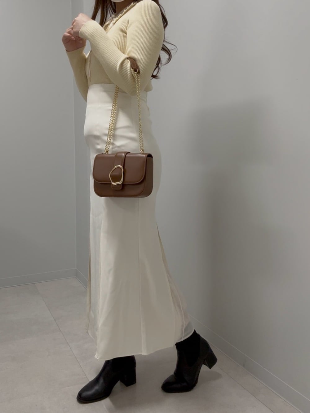 ブラウン系のショルダーバッグ、イエロー系のニット/セーター、ホワイト系のスカートを着用したレディースの春コーディネートの2枚目の写真