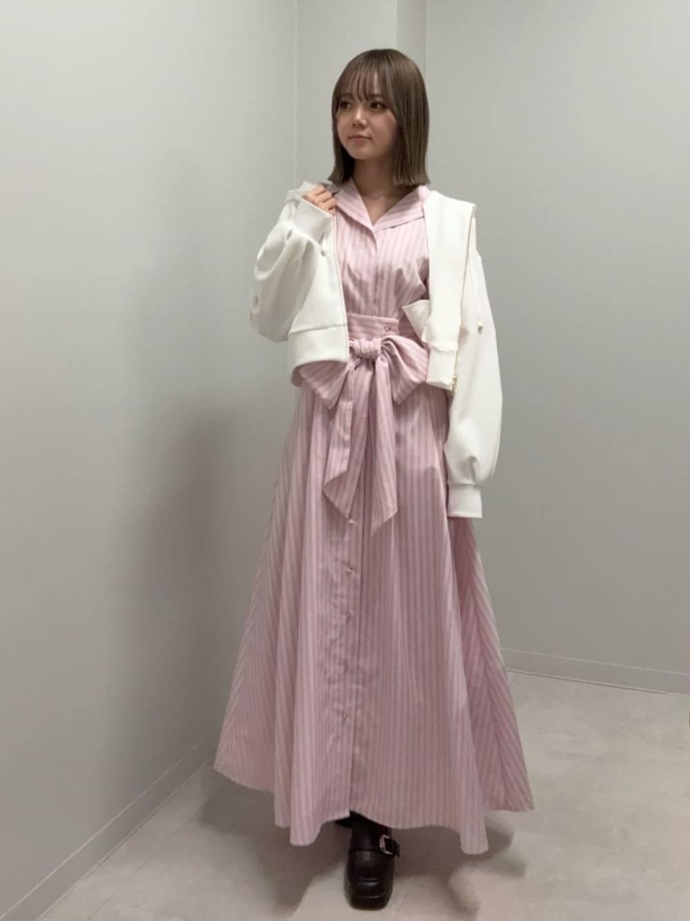 ピンク系のワンピース、ホワイト系のパーカーを着用したレディースの春コーディネートの2枚目の写真