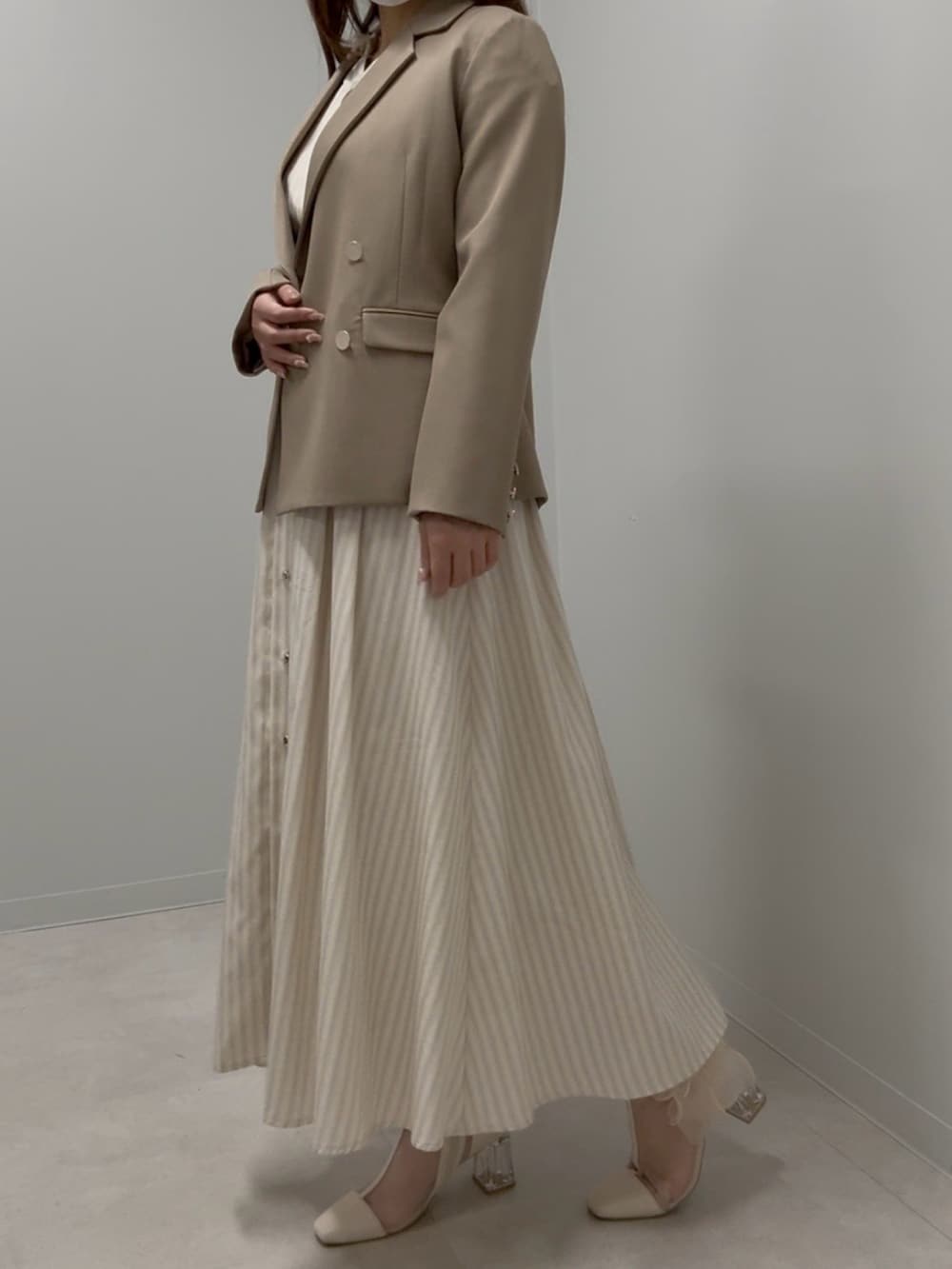 ブラウン系のテーラードジャケット、ベージュ系のワンピース、ベージュ系のブーツを着用したレディースの春コーディネートの2枚目の写真