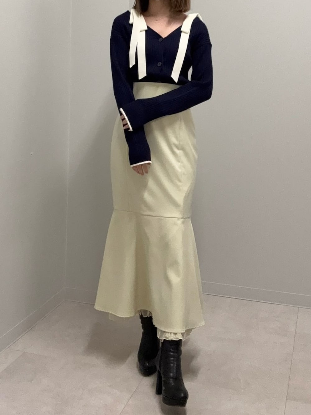 ブルー系のニット/セーター、イエロー系のスカート、ブラック系のブーツを着用したレディースの春コーディネートの3枚目の写真