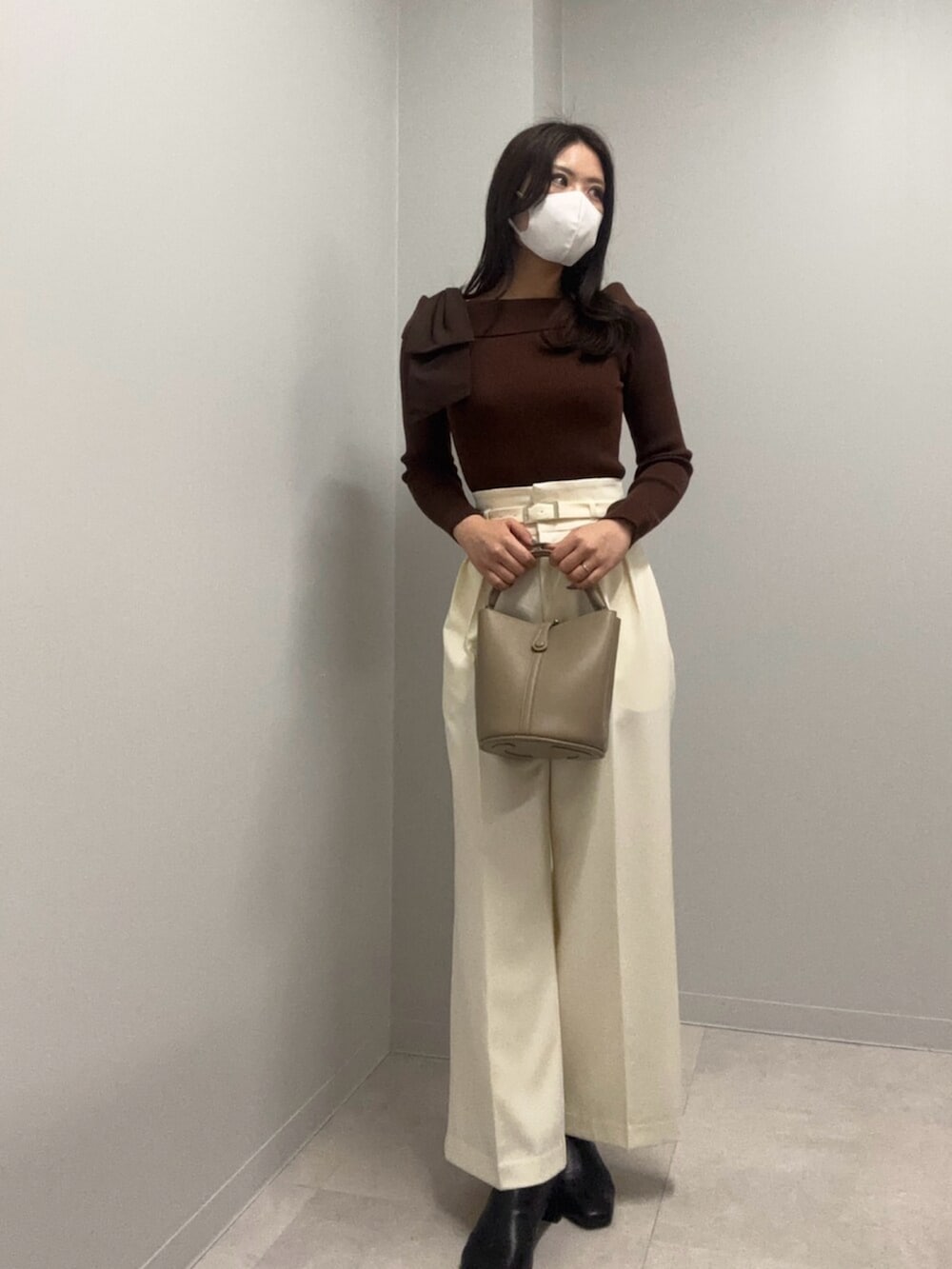 ブラウン系のニット/セーター、ホワイト系のその他パンツ、ベージュ系のショルダーバッグを着用したレディースの春コーディネートの2枚目の写真