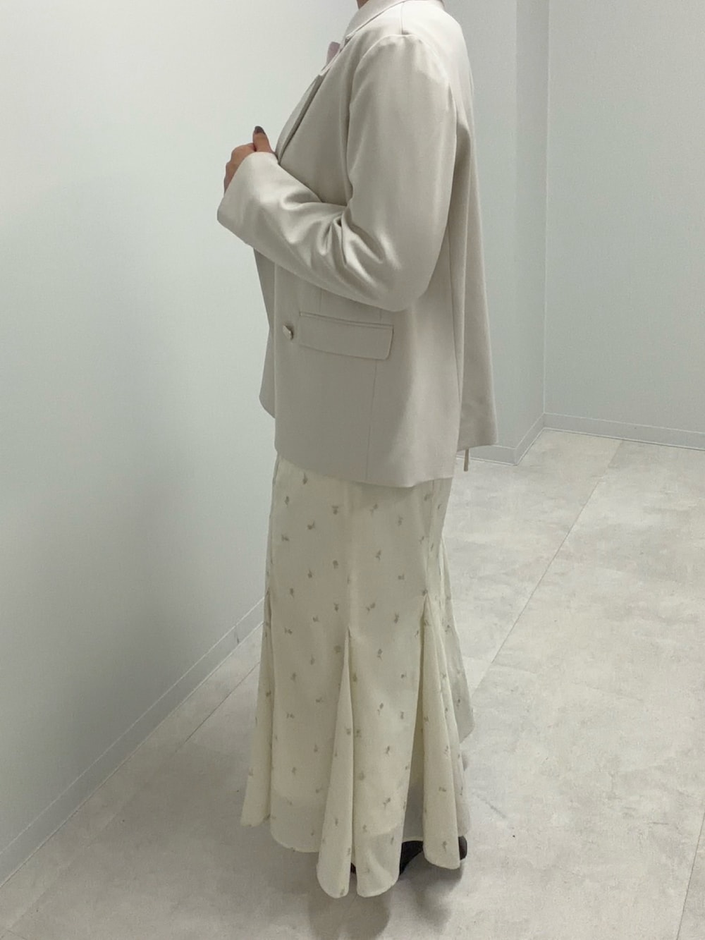 ベージュ系のテーラードジャケット、ホワイト系のスカート、ピンク系のニット/セーターを着用したレディースの春コーディネートの2枚目の写真