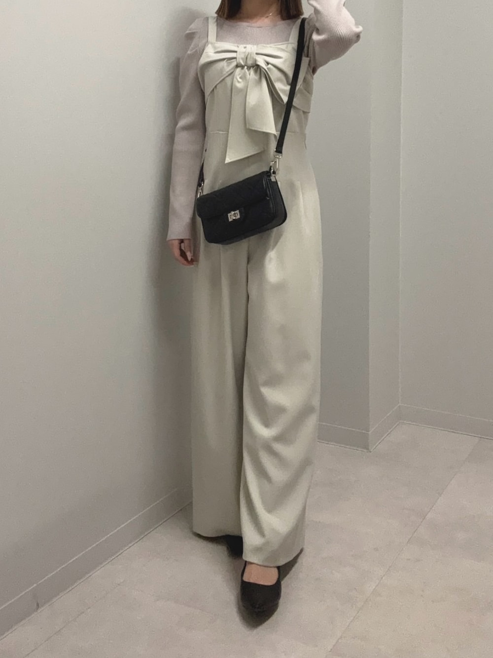 グレー系のニット/セーター、ベージュ系のつなぎ/オールインワン、ブラック系のショルダーバッグを着用したレディースの春コーディネートの3枚目の写真