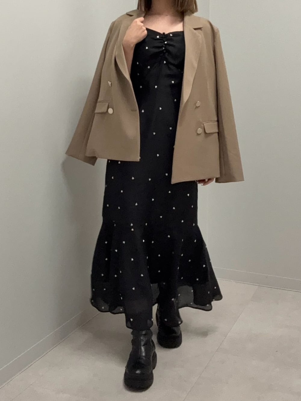 ブラウン系のテーラードジャケット、ブラック系のワンピース、ブラック系のブーツを着用したレディースの春コーディネートの2枚目の写真