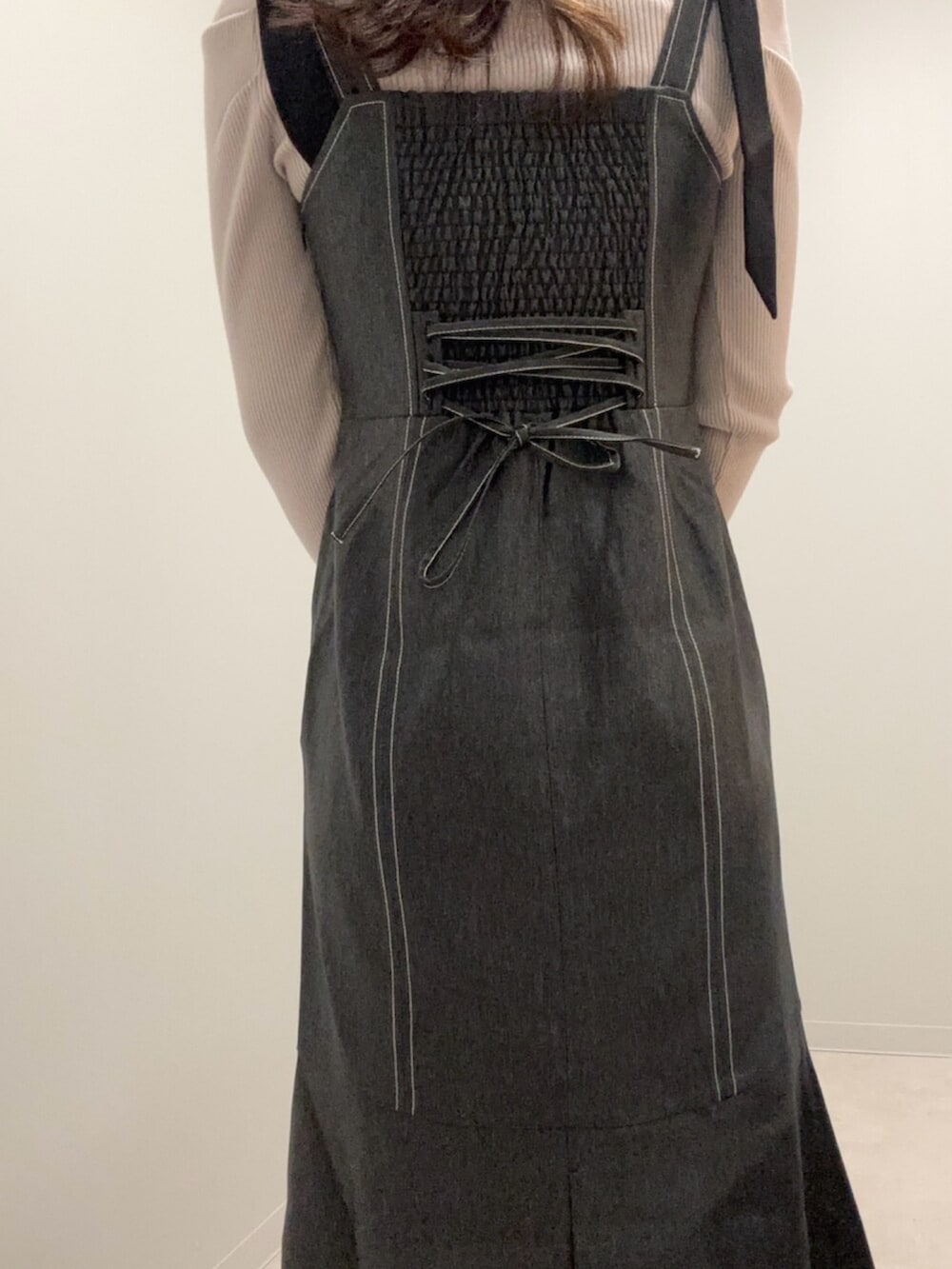 グレー系のニット/セーター、ブラック系のジャンパースカートを着用したレディースの春コーディネートの3枚目の写真