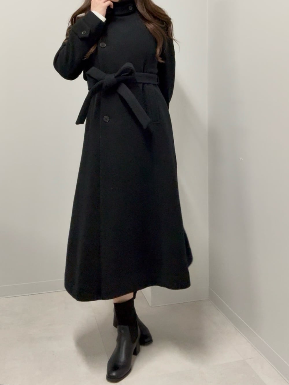 ブラック系のブーツ、ブラック系のステンカラーコートを着用したレディースの冬コーディネートの2枚目の写真