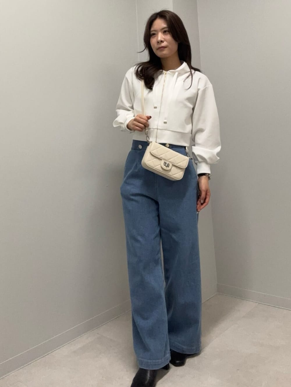 ブルー系のデニムパンツ、ホワイト系のパーカーを着用したレディースの春コーディネートの3枚目の写真