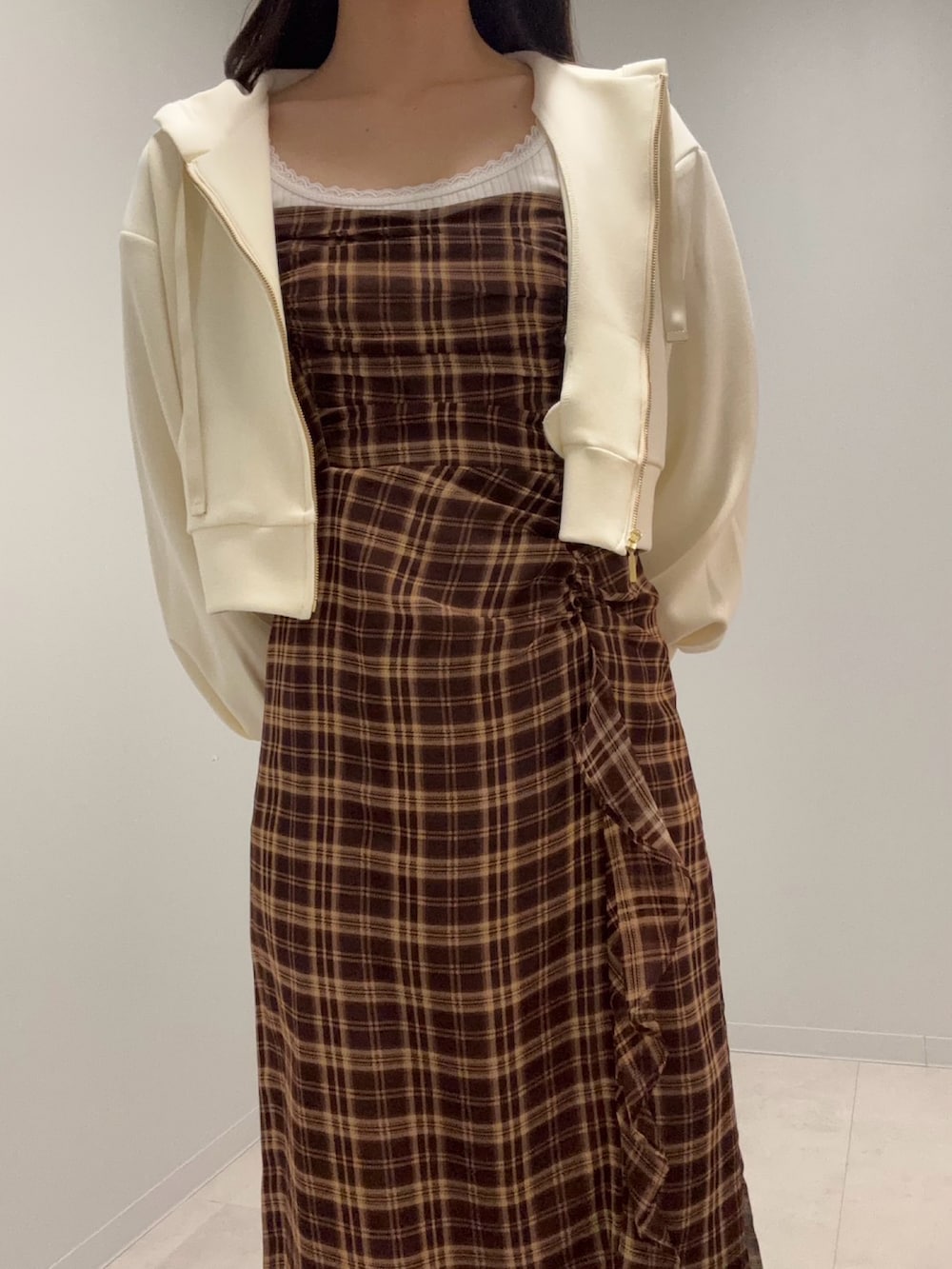 イエロー系のパーカー、ブラウン系のワンピースを着用したレディースの春コーディネートの3枚目の写真