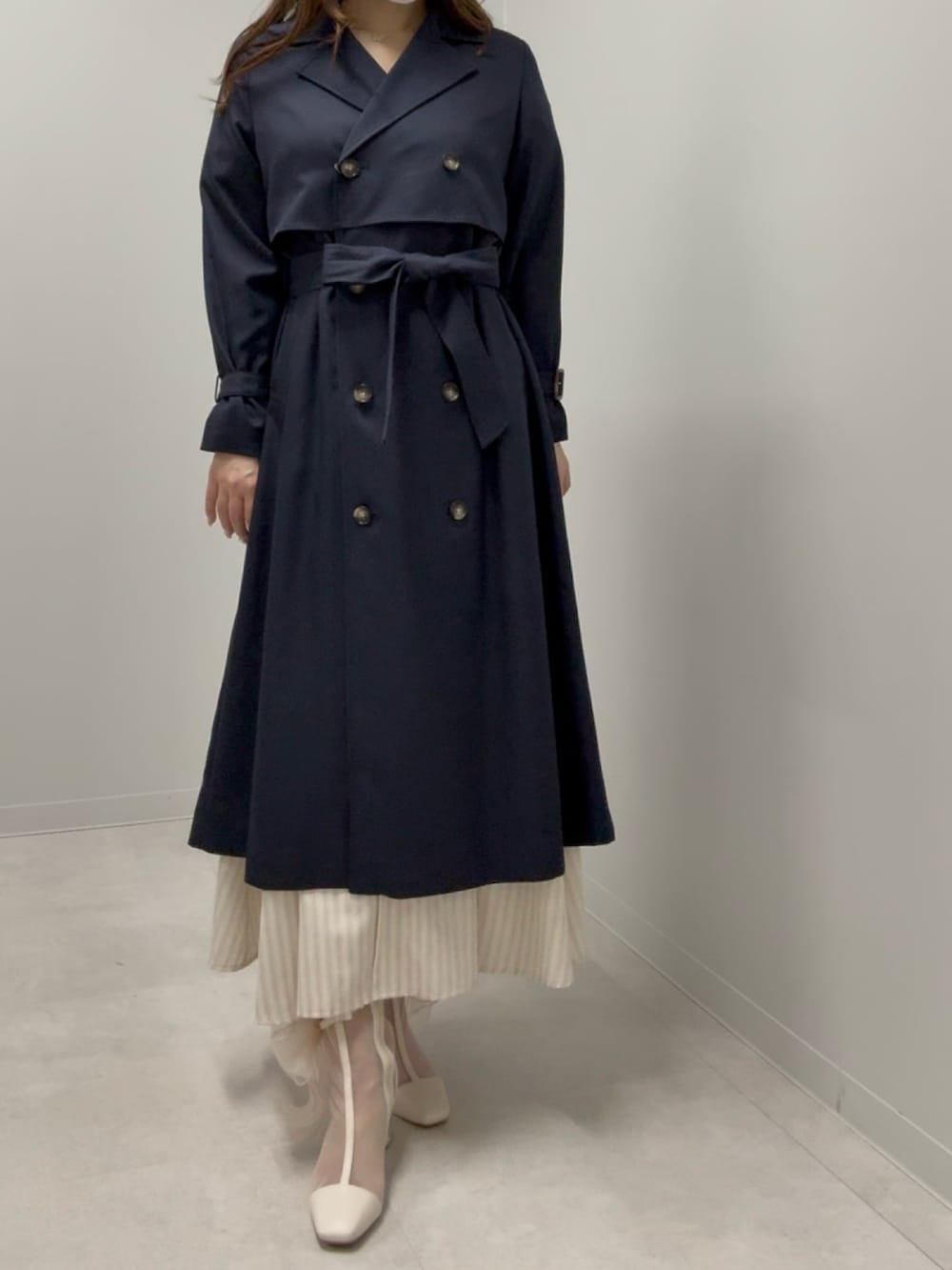 ブルー系のトレンチコート、ベージュ系のブーツを着用したレディースの春コーディネートの2枚目の写真