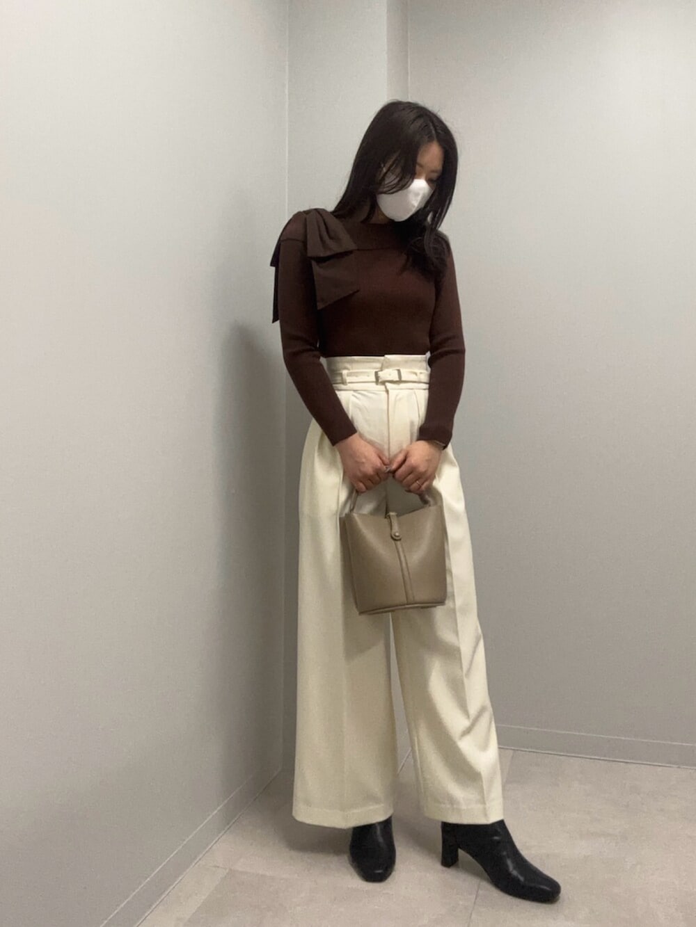 ブラウン系のニット/セーター、ホワイト系のその他パンツ、ベージュ系のショルダーバッグを着用したレディースの春コーディネートの3枚目の写真