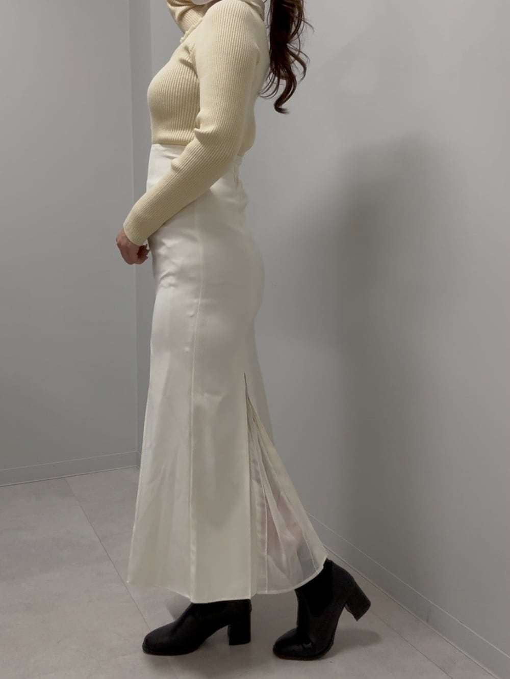 ブラウン系のショルダーバッグ、イエロー系のニット/セーター、ホワイト系のスカートを着用したレディースの春コーディネートの3枚目の写真